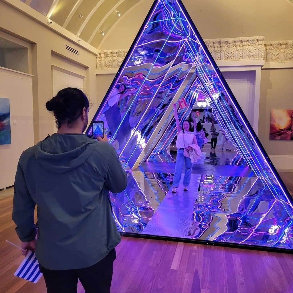 Visitors inside the mirror pyramid light installation at The Coliseum of Art
