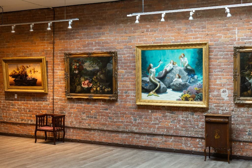 Inside the Occidental Fine Arts Center, framed paintings hang on exposed brick walls above the open wood floor.